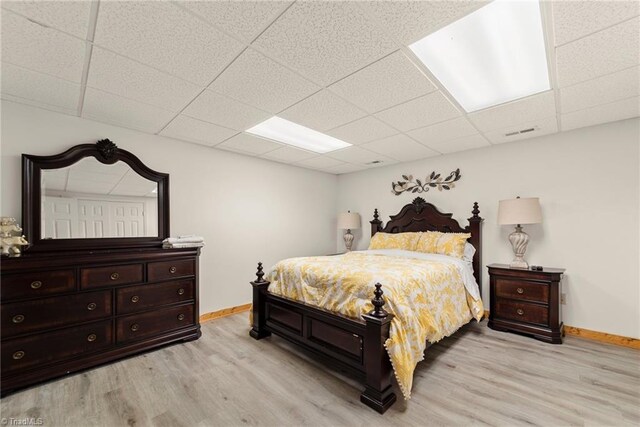 bedroom with light hardwood / wood-style floors and a drop ceiling