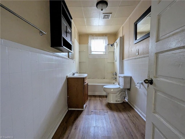 423 Tate St, High Point, NC 27260 - bathroom featuring tile walls, wood finished floors, vanity, shower / bath combination, and wainscoting