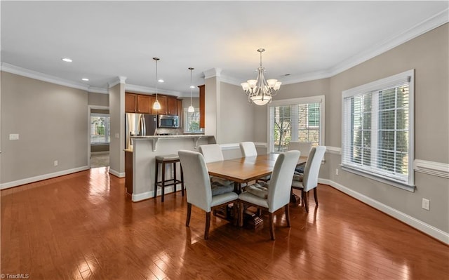 dining space with wood-type flooring, crown molding, baseboards, and an inviting chandelier