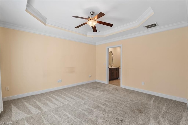 carpeted spare room with baseboards, visible vents, a ceiling fan, a raised ceiling, and crown molding