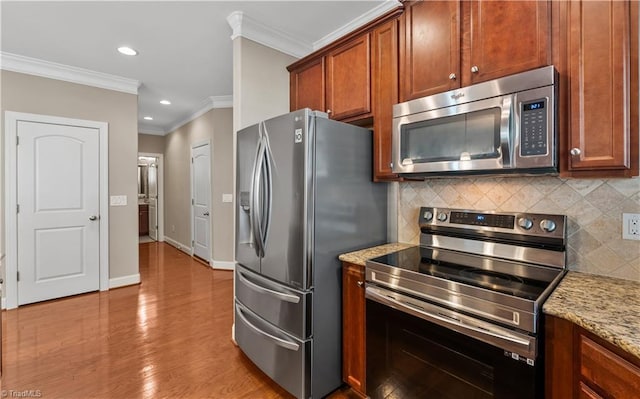 kitchen with tasteful backsplash, baseboards, ornamental molding, wood finished floors, and stainless steel appliances