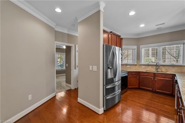 kitchen featuring a sink, appliances with stainless steel finishes, decorative backsplash, dark wood finished floors, and crown molding