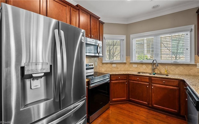 kitchen featuring a sink, appliances with stainless steel finishes, decorative backsplash, dark wood finished floors, and crown molding