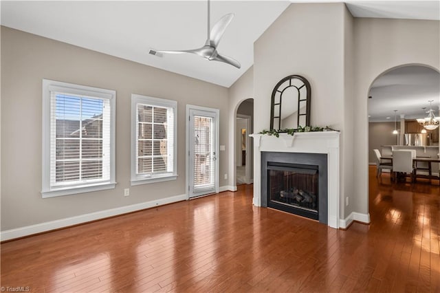 unfurnished living room featuring a fireplace, visible vents, hardwood / wood-style floors, baseboards, and ceiling fan with notable chandelier