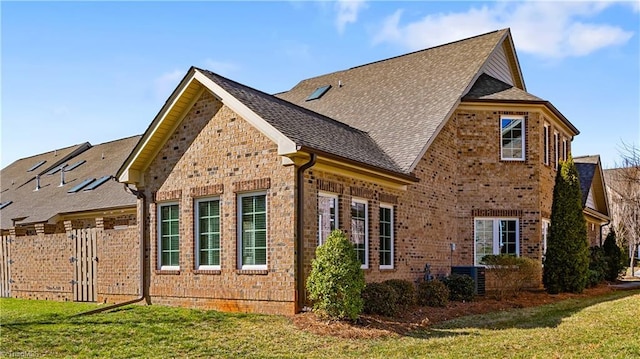 view of property exterior featuring a yard, a shingled roof, and brick siding