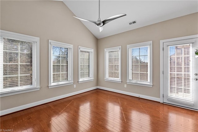 spare room featuring baseboards, visible vents, a ceiling fan, hardwood / wood-style flooring, and vaulted ceiling