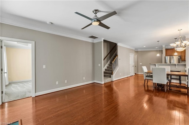 living room featuring crown molding, wood-type flooring, visible vents, baseboards, and stairs