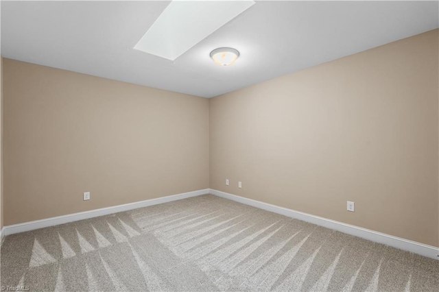 unfurnished room featuring carpet floors, a skylight, and baseboards