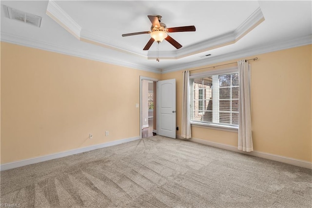 carpeted spare room with a raised ceiling, visible vents, ornamental molding, ceiling fan, and baseboards