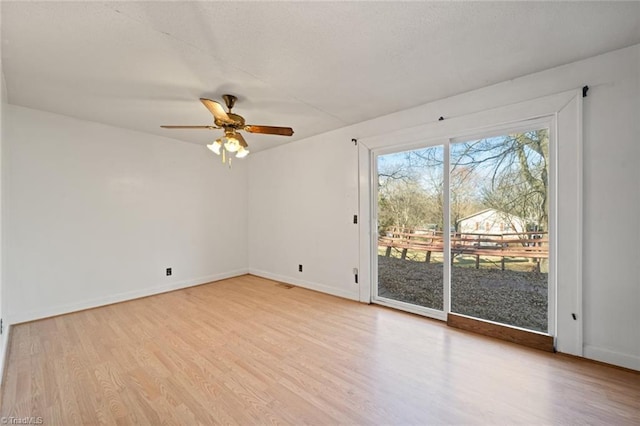 spare room featuring baseboards, light wood-style floors, ceiling fan, and a textured ceiling