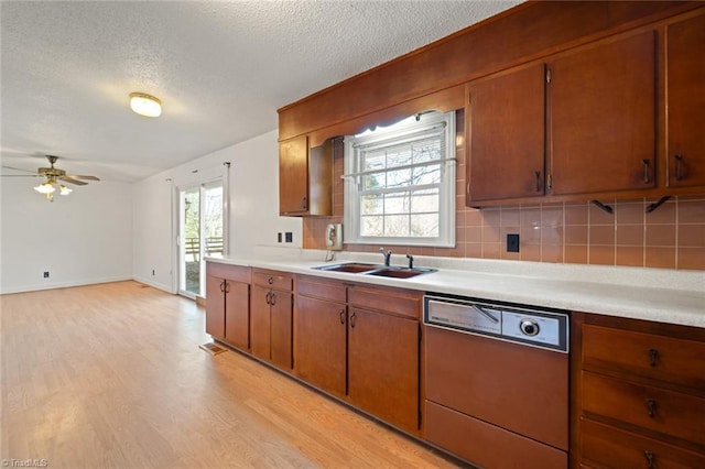 kitchen featuring dishwasher, light countertops, plenty of natural light, and a sink