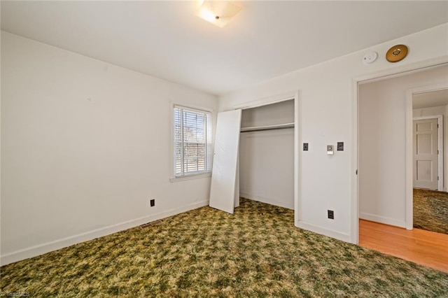 unfurnished bedroom with carpet, wood finished floors, baseboards, and a closet