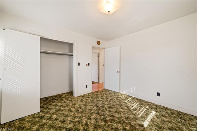 unfurnished bedroom with carpet flooring, baseboards, and a closet