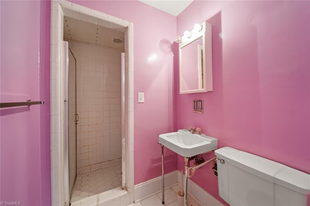 bathroom with baseboards, toilet, a shower stall, and tile patterned flooring