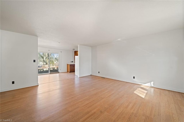 spare room featuring baseboards and light wood-style flooring