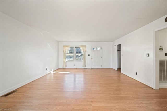 unfurnished living room featuring visible vents, light wood-style flooring, and baseboards