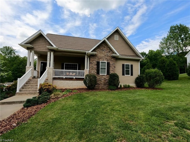 craftsman house with a front yard, a porch, stone siding, and roof with shingles