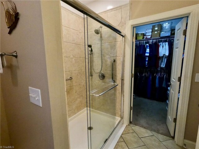 full bathroom featuring a stall shower, tile patterned flooring, and a walk in closet