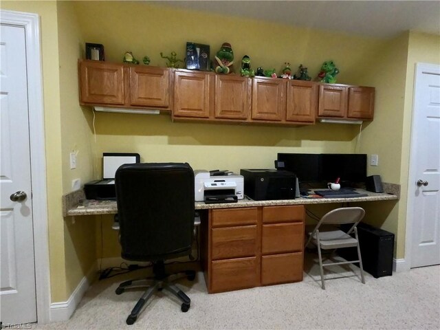 office space featuring built in desk, baseboards, and light colored carpet