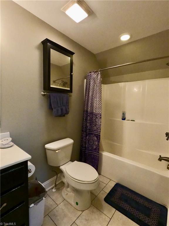 bathroom featuring tile patterned floors, toilet, vanity, shower / bath combination with curtain, and baseboards