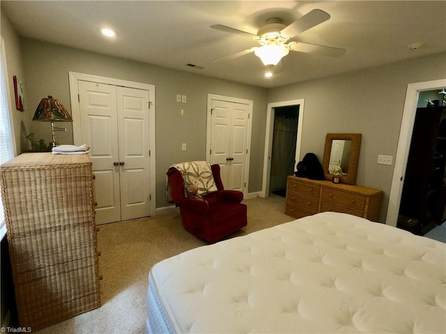 bedroom with a ceiling fan, recessed lighting, light colored carpet, and two closets