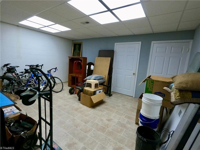below grade area with a drop ceiling and concrete block wall