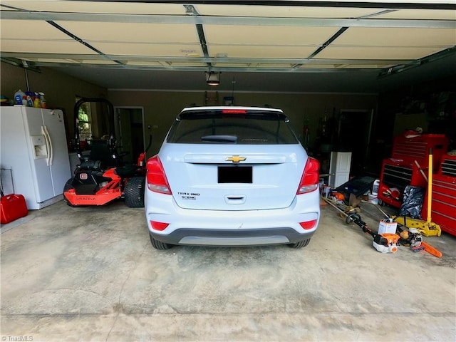 garage featuring white refrigerator with ice dispenser and a garage door opener