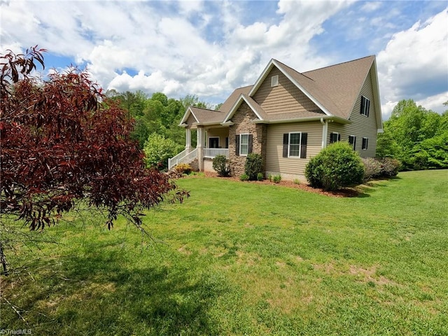 rear view of property with a yard, covered porch, and stone siding