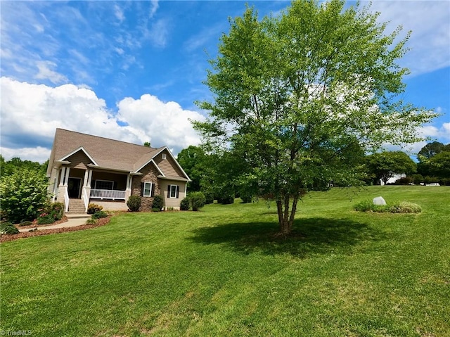 view of front of property with a front yard, covered porch, and brick siding
