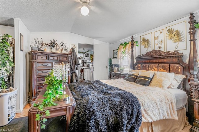 bedroom with ceiling fan, vaulted ceiling, and a textured ceiling