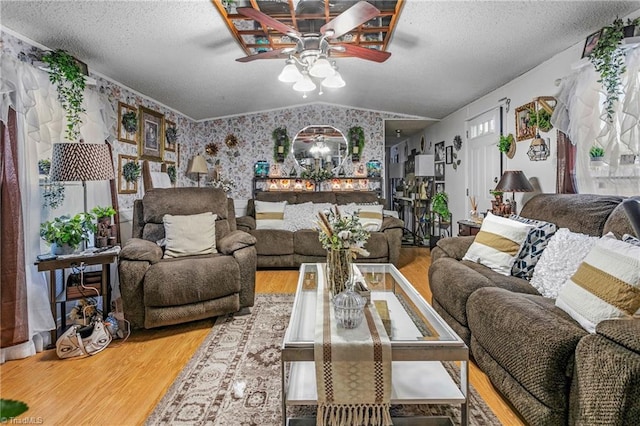 living room with ceiling fan, lofted ceiling, hardwood / wood-style floors, and a textured ceiling