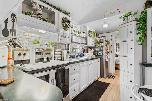 kitchen with vaulted ceiling, white cabinetry, stainless steel appliances, a textured ceiling, and light hardwood / wood-style flooring