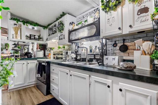 kitchen with white cabinetry, sink, electric range, and light hardwood / wood-style flooring