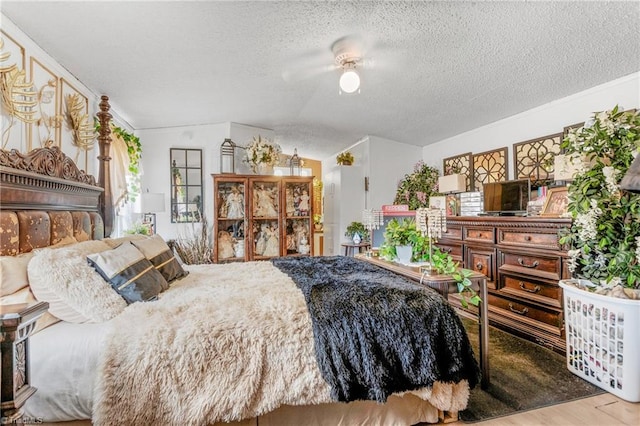 bedroom featuring hardwood / wood-style floors, vaulted ceiling, and a textured ceiling