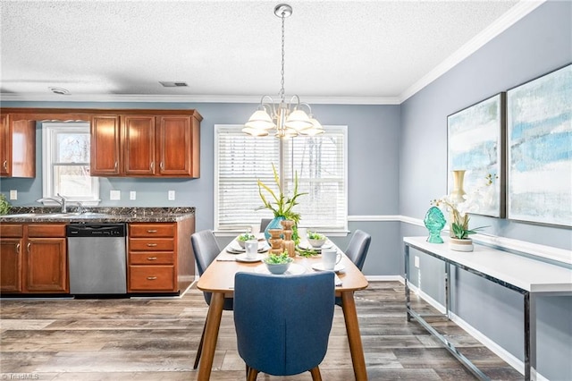 kitchen featuring visible vents, dishwasher, brown cabinets, wood finished floors, and a sink