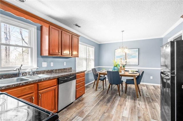 kitchen featuring brown cabinets, light wood finished floors, stainless steel dishwasher, freestanding refrigerator, and a sink