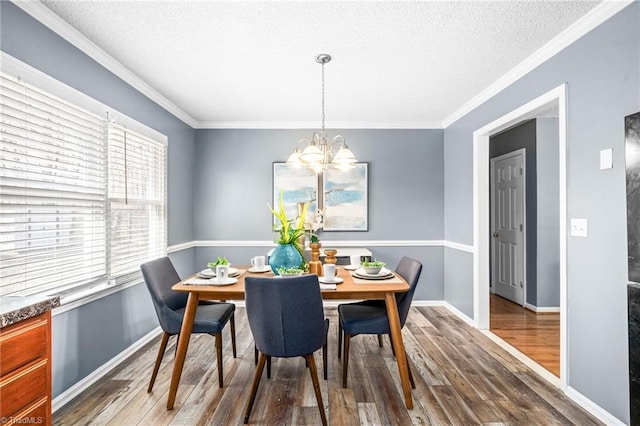 dining space featuring ornamental molding, wood finished floors, and an inviting chandelier