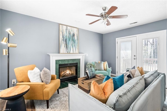 sitting room featuring a ceiling fan, a high end fireplace, and visible vents