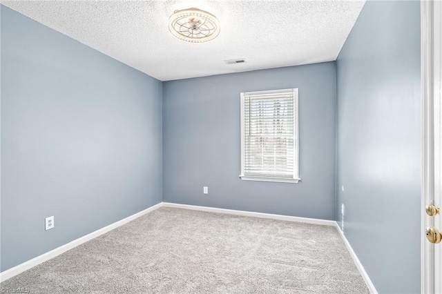 empty room with carpet floors, visible vents, baseboards, and a textured ceiling