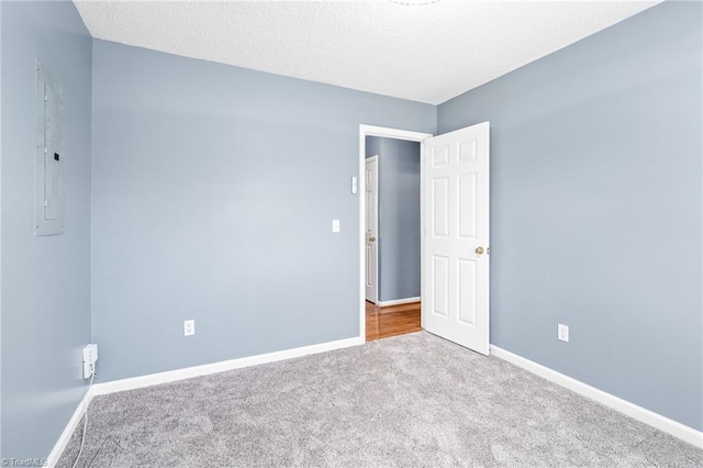 spare room with carpet, a textured ceiling, and baseboards