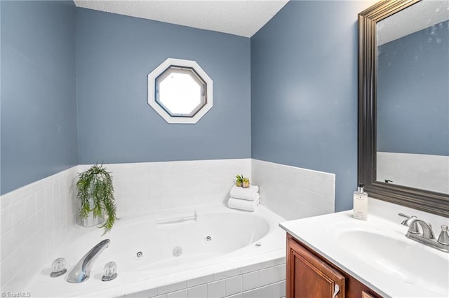 full bathroom with a textured ceiling, a tub with jets, and vanity