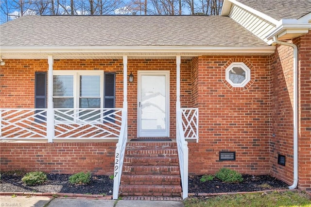 property entrance with crawl space, brick siding, and roof with shingles