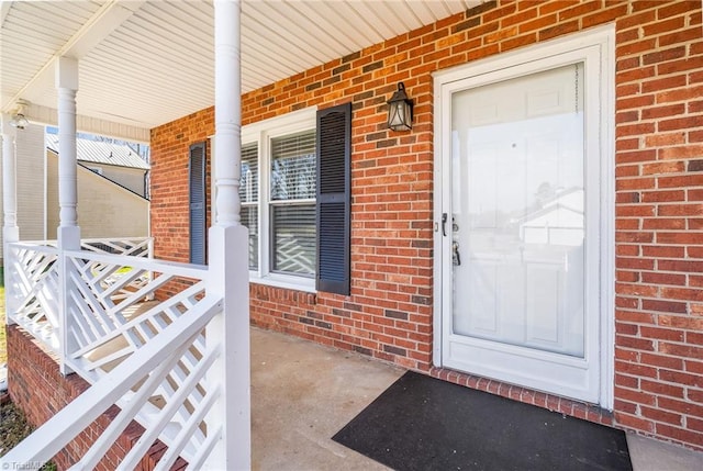 property entrance with covered porch and brick siding