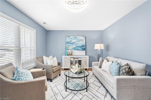 living room with visible vents, a textured ceiling, and baseboards