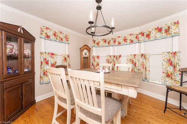 dining space with light hardwood / wood-style floors, ornamental molding, and an inviting chandelier