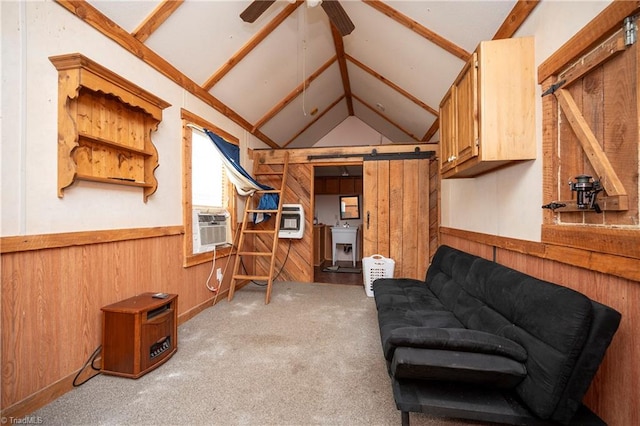 living room featuring ceiling fan, wooden walls, lofted ceiling with beams, light carpet, and a barn door