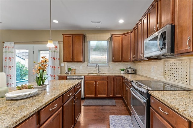 kitchen with dark wood finished floors, light stone counters, stainless steel appliances, and a sink