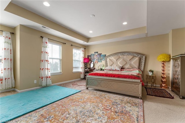 carpeted bedroom with a tray ceiling, recessed lighting, visible vents, and baseboards