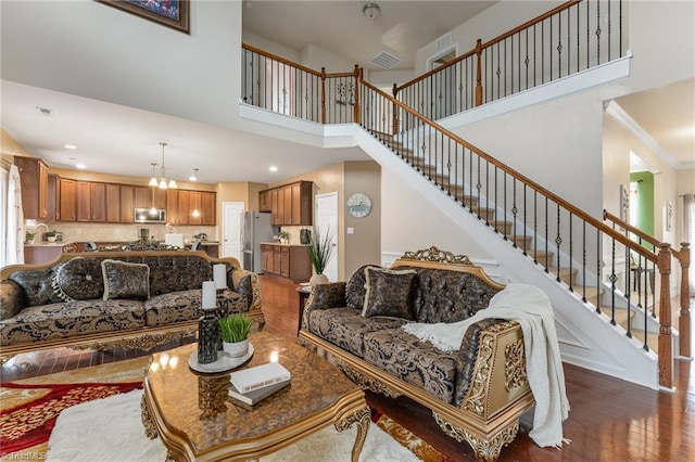 living area with a notable chandelier, stairs, wood finished floors, and recessed lighting