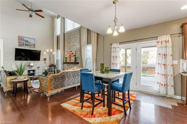 dining area featuring plenty of natural light, a high ceiling, hardwood / wood-style floors, and ceiling fan with notable chandelier